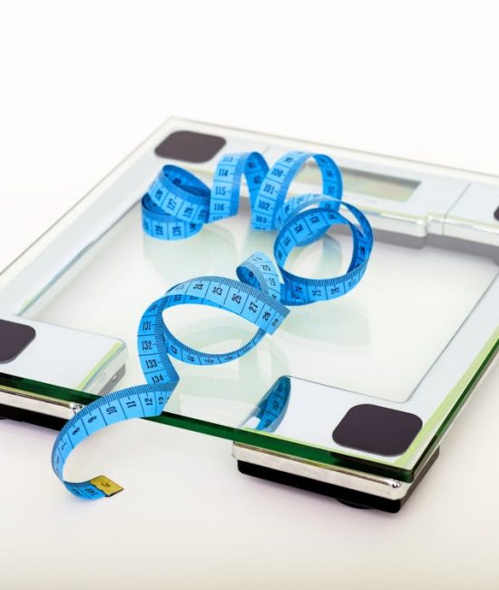 Free A digital glass weighing scale with a blue measuring tape, symbolizing weight management. Stock Photo