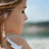 shallow focus photography of woman wearing dangling earrings holding her hair near mountain