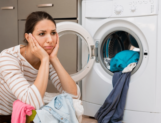 A stressed lady sitting near washing machine